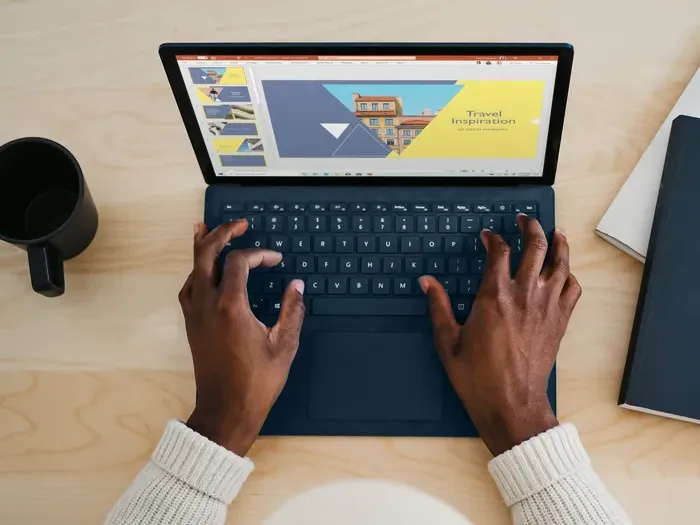 Hands typing on a laptop with slides open, preparing content and updating a local business directory listing